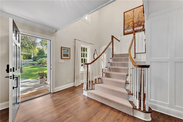 foyer entrance with crown molding and hardwood / wood-style floors