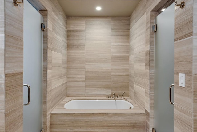 bathroom featuring shower with separate bathtub and tile walls