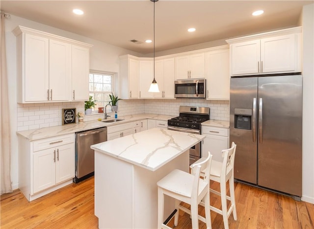 kitchen featuring pendant lighting, light wood-type flooring, stainless steel appliances, and sink