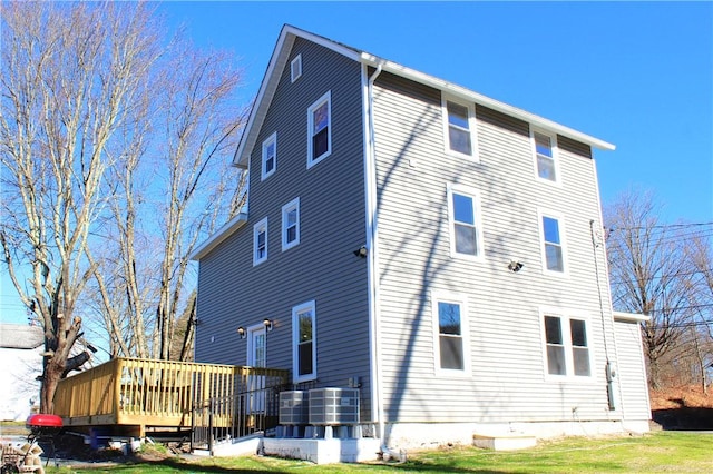 back of property with a yard, cooling unit, and a deck