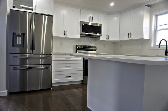 kitchen with backsplash, white cabinetry, dark wood-type flooring, and appliances with stainless steel finishes