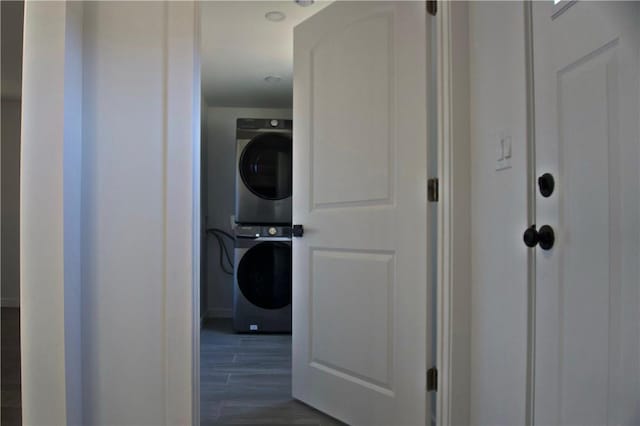 laundry room with stacked washer and dryer and dark hardwood / wood-style floors