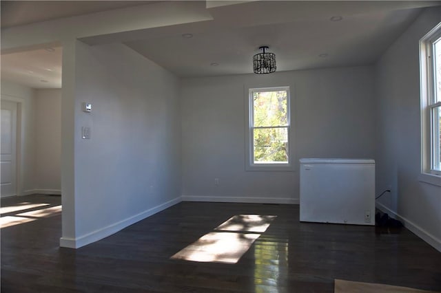 unfurnished room featuring dark wood-type flooring and a notable chandelier