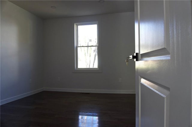 spare room featuring a wealth of natural light and dark wood-type flooring