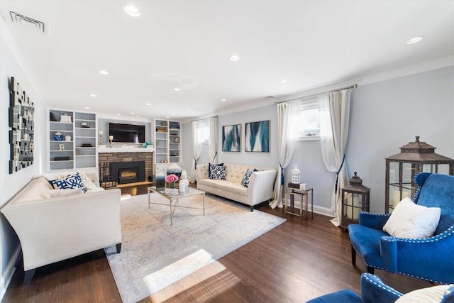 living room featuring a fireplace, dark hardwood / wood-style flooring, built in features, and crown molding