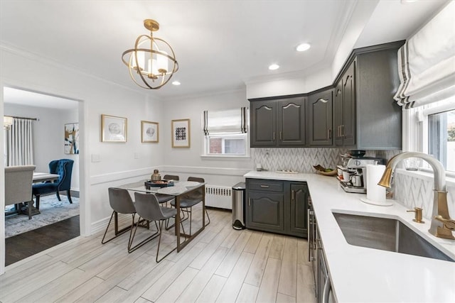 kitchen with sink, radiator heating unit, crown molding, a chandelier, and light wood-type flooring