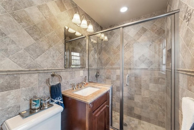 bathroom with decorative backsplash, a shower with door, vanity, and tile walls