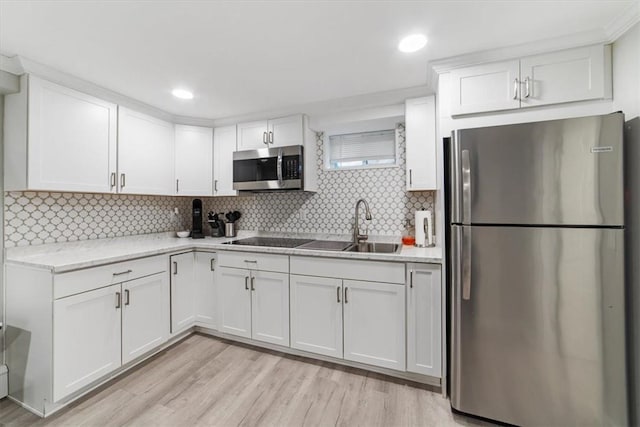 kitchen featuring backsplash, white cabinets, stainless steel appliances, and light hardwood / wood-style floors