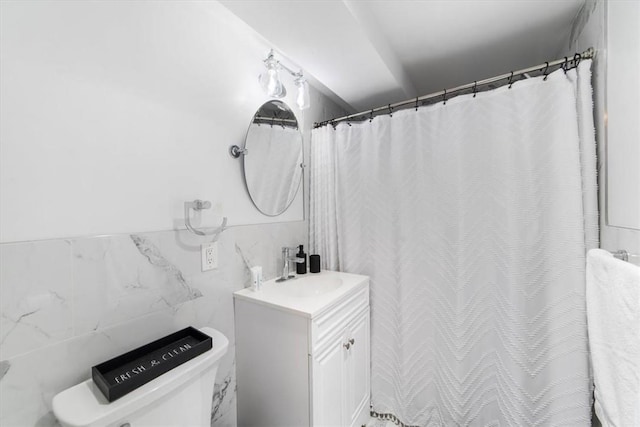 bathroom featuring vanity, toilet, and tile walls