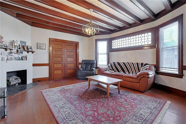 living room featuring beamed ceiling, hardwood / wood-style floors, and an inviting chandelier