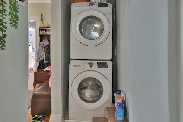 laundry area featuring wood-type flooring and stacked washer / dryer