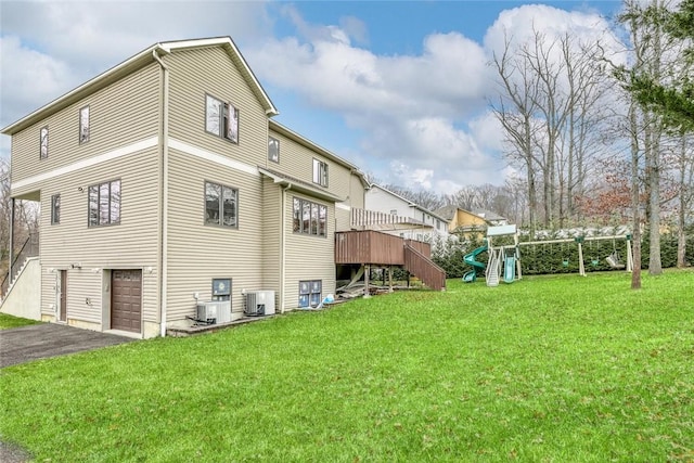 back of property featuring a playground, a yard, cooling unit, and a garage