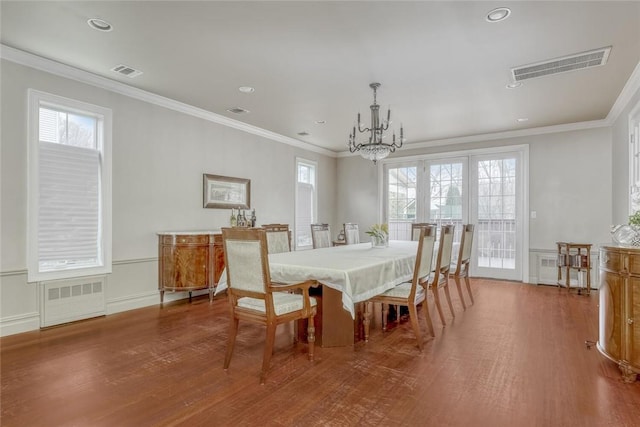 dining space featuring hardwood / wood-style flooring, crown molding, and a chandelier