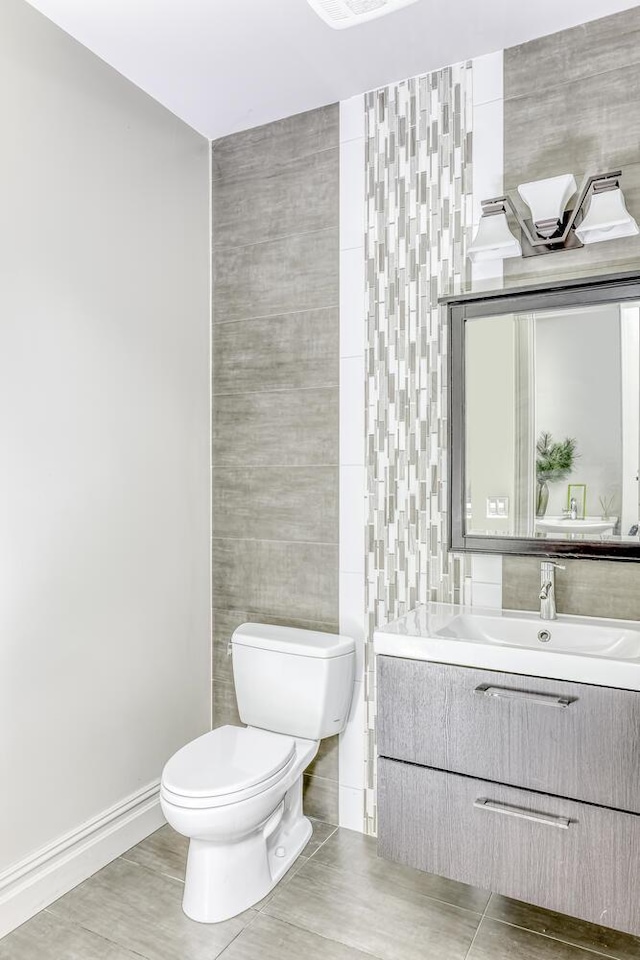 bathroom featuring vanity, toilet, and tile walls