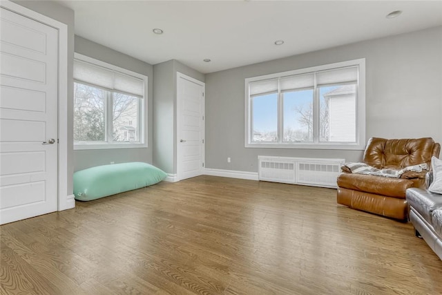 living area featuring radiator heating unit, a wealth of natural light, and hardwood / wood-style floors