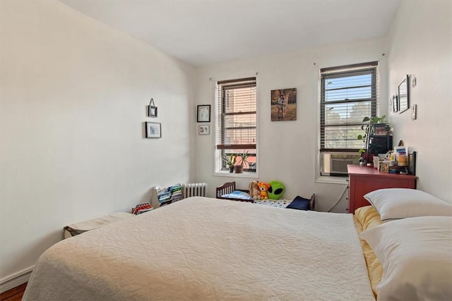 bedroom featuring cooling unit, wood-type flooring, and multiple windows