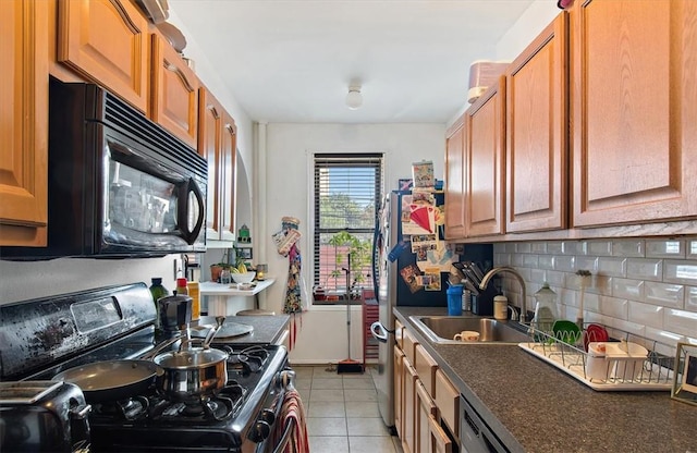 kitchen featuring decorative backsplash, light tile patterned floors, sink, and black appliances