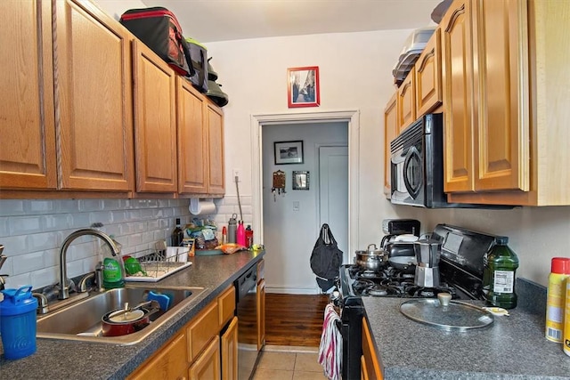 kitchen featuring decorative backsplash, stove, light wood-type flooring, stainless steel dishwasher, and sink