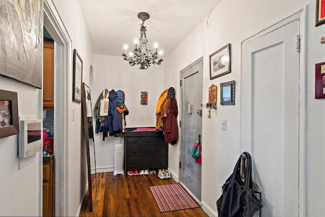 hallway featuring a chandelier and dark wood-type flooring