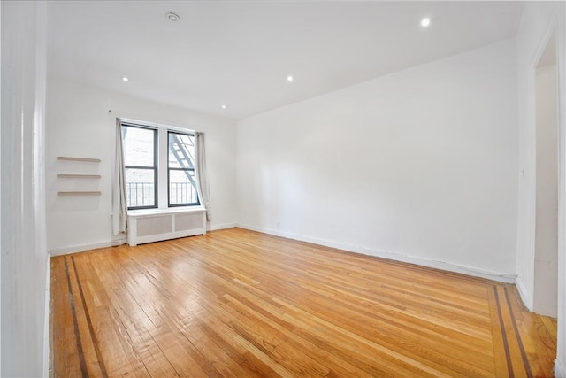 spare room with radiator heating unit and light hardwood / wood-style flooring