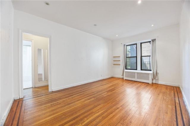 empty room featuring radiator heating unit and light hardwood / wood-style floors