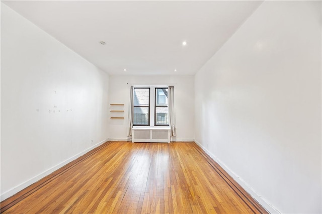 empty room with radiator heating unit and light hardwood / wood-style floors