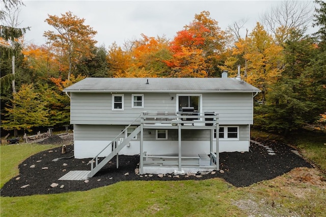 rear view of house featuring a lawn and a wooden deck