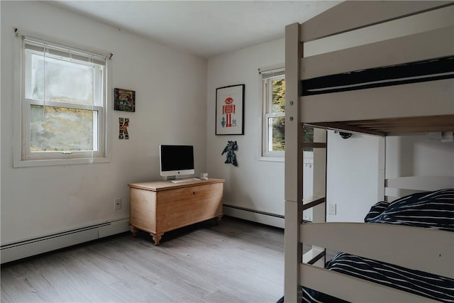 bedroom featuring a baseboard heating unit and light hardwood / wood-style flooring