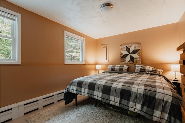 bedroom featuring multiple windows and a baseboard heating unit