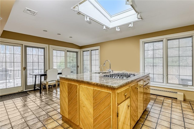 kitchen with a wealth of natural light, a skylight, a kitchen island with sink, and a baseboard heating unit