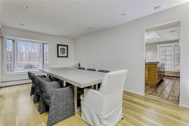 dining area with a healthy amount of sunlight, light hardwood / wood-style floors, and a baseboard heating unit