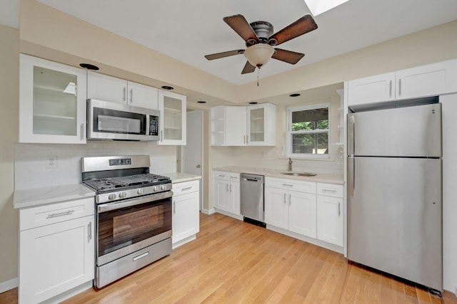 kitchen with light hardwood / wood-style flooring, white cabinets, stainless steel appliances, and sink