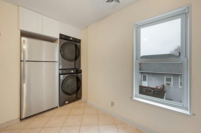 laundry area featuring light tile patterned floors and stacked washer / drying machine