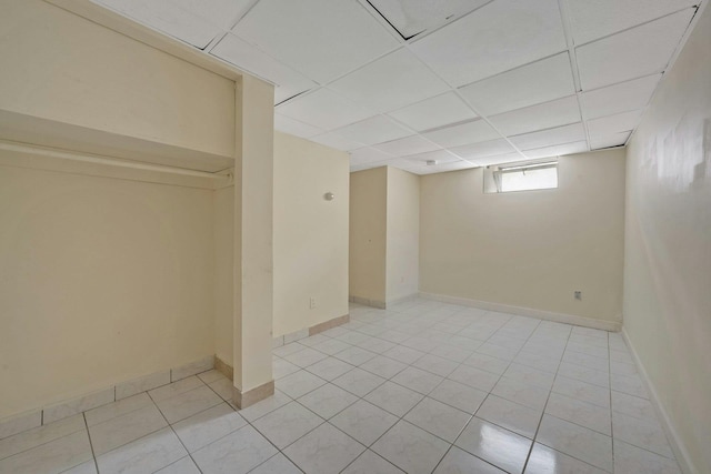 basement featuring light tile patterned floors and a paneled ceiling