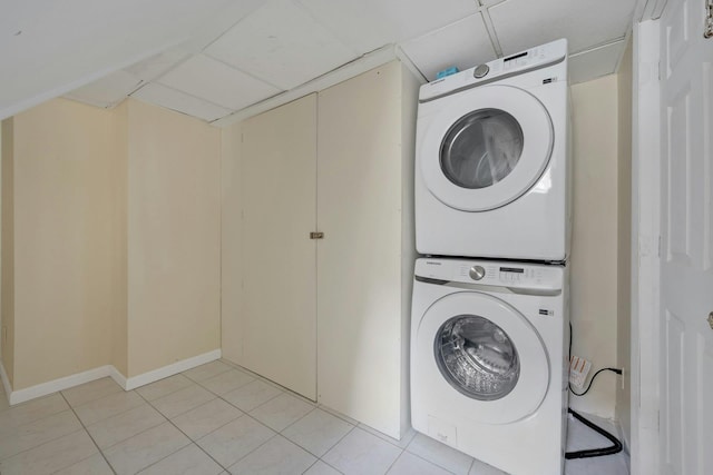 clothes washing area featuring light tile patterned flooring and stacked washing maching and dryer