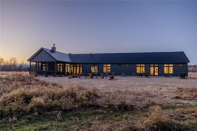 back house at dusk with a sunroom