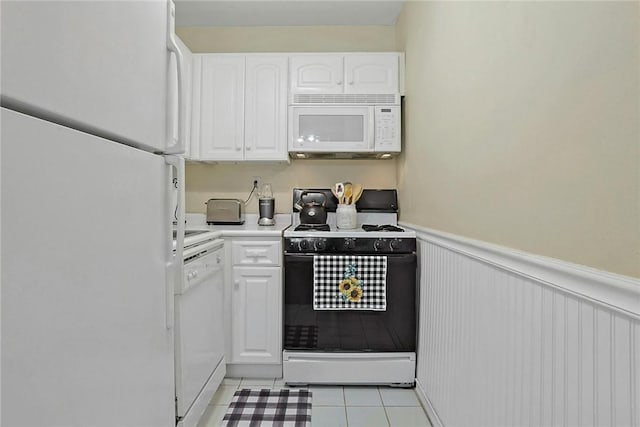 kitchen with white cabinetry, light tile patterned flooring, and white appliances