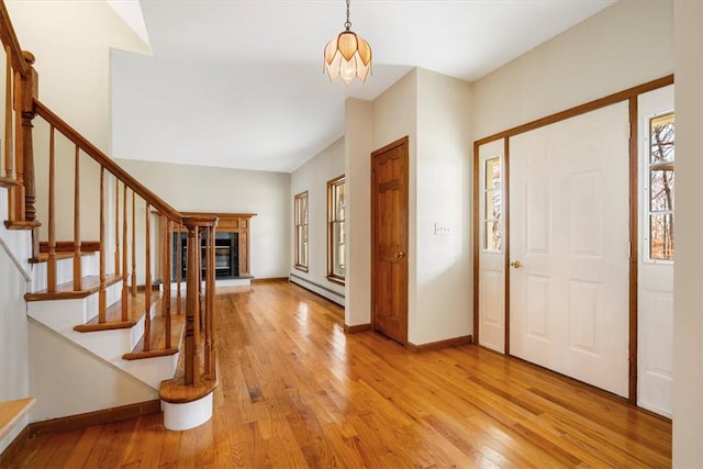 entrance foyer featuring baseboard heating, light hardwood / wood-style flooring, and an inviting chandelier