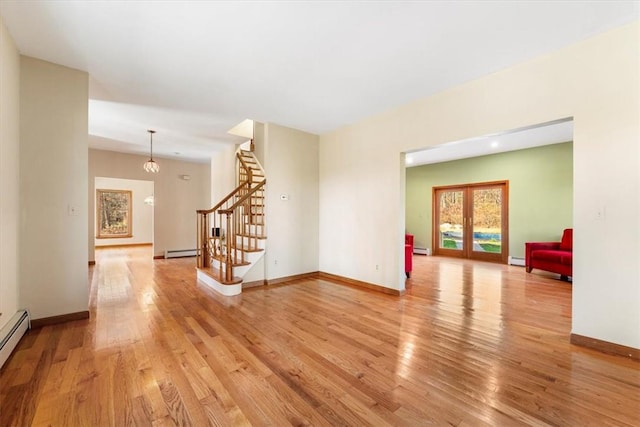 empty room featuring french doors, a baseboard heating unit, and light wood-type flooring