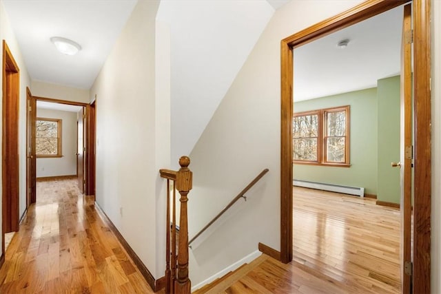 corridor featuring lofted ceiling, light wood-type flooring, and baseboard heating