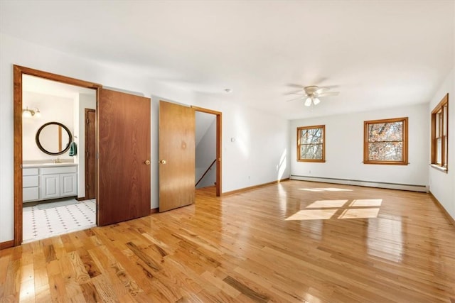 unfurnished room with ceiling fan, a baseboard heating unit, and light hardwood / wood-style flooring