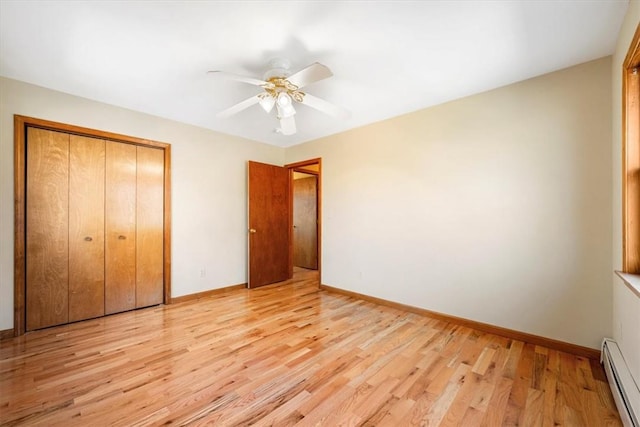 unfurnished bedroom featuring a closet, light hardwood / wood-style flooring, baseboard heating, and ceiling fan