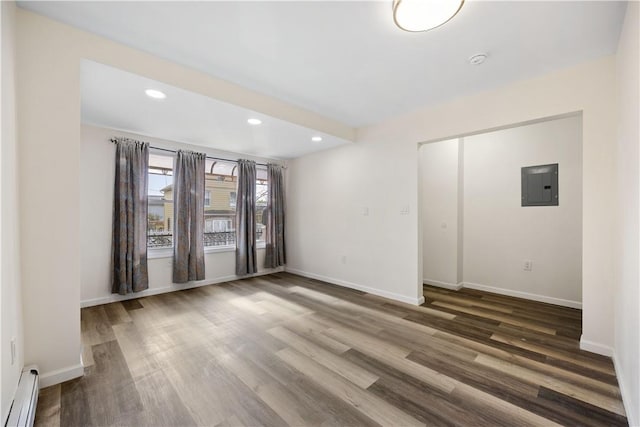 empty room with baseboard heating, electric panel, and dark wood-type flooring