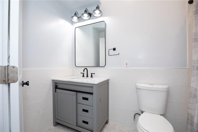 bathroom with vanity, tile walls, and toilet