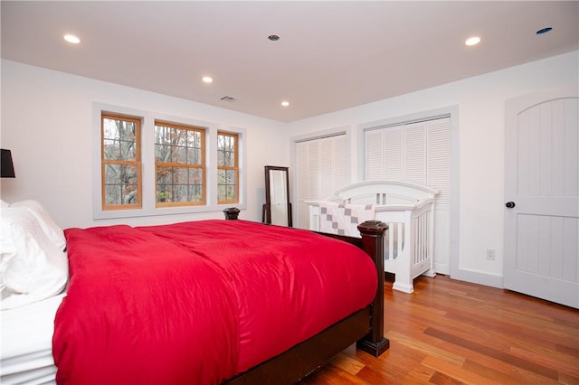 bedroom with multiple closets and wood-type flooring