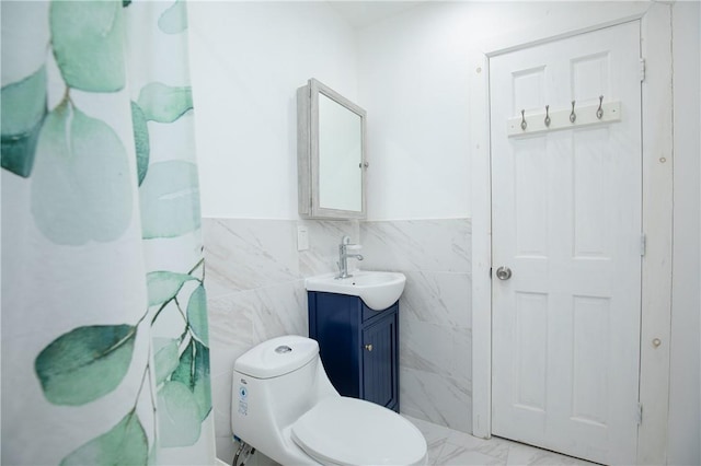 bathroom with walk in shower, vanity, tile walls, and toilet