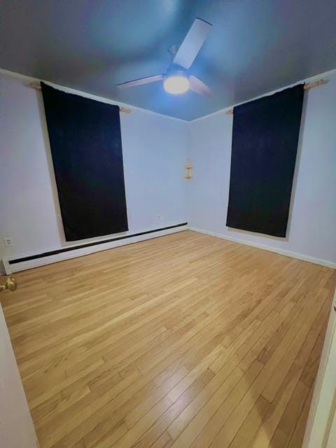 empty room featuring a baseboard radiator, light hardwood / wood-style flooring, and ceiling fan