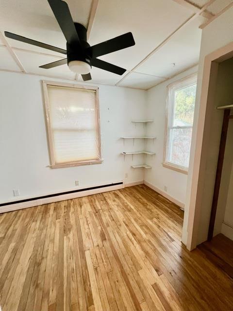 empty room with hardwood / wood-style floors, ceiling fan, and baseboard heating