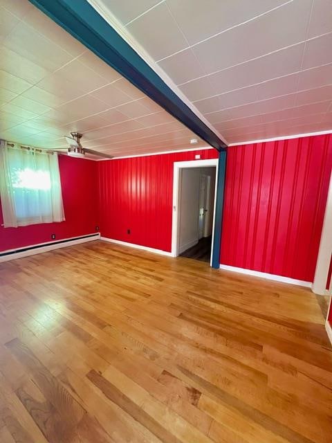 empty room with hardwood / wood-style floors, ceiling fan, beam ceiling, and baseboard heating