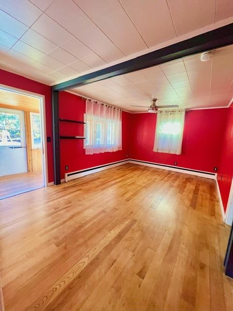 spare room with hardwood / wood-style flooring, ceiling fan, and a baseboard heating unit